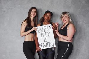 behalte das im Kopf. Gruppe multiethnischer Frauen, die im Studio vor grauem Hintergrund stehen foto