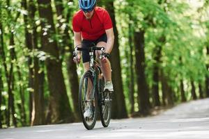 Wochenendaktivitäten. Radfahrer auf dem Fahrrad ist an sonnigen Tagen auf der Asphaltstraße im Wald foto