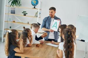 einen Brief zeigen. gruppe von kinderschülern im unterricht in der schule mit lehrer foto