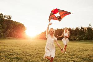 Spaß haben in der Urlaubszeit. Mutter und Tochter mit Drachen im Feld. schöne Natur foto