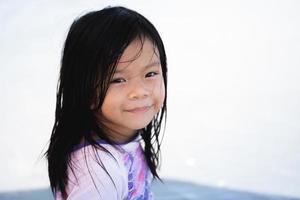 Porträtbild Kind 5 Jahre alt. positives lächelndes kleines mädchen, das kamera betrachtet. Kind sitzt am Strand, hübsche Kinder im Vorschulalter mit schönem, glücklichem Gesicht, das allein auf See posiert, fröhlicher Baby-Kopfschuss. foto