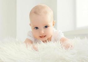 Nahaufnahmeporträt des Säuglings, der zu Hause im weißen Raum liegt