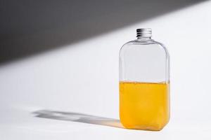 Trinken Sie in einer Glasflasche auf weißem Hintergrund mit harten oder harten Schatten und Sonnenlicht von Blättern, die auf die Wand fallen. modernes und minimalistisches Produktdesign. kaltes Erfrischungsgetränk. foto