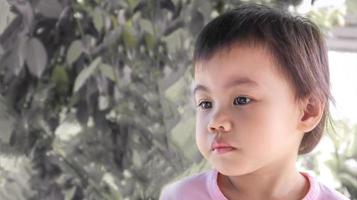 trauriges 3-jähriges süßes asiatisches mädchen, kleines kleinkind mit entzückenden kurzen haaren, die nach links schauen. foto