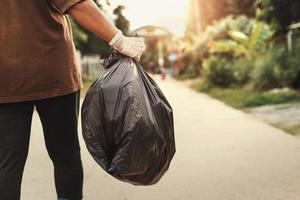 frauenhand, die müllbeutel zum recyceln in den müll hält foto