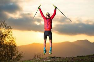 Sportler macht bei Sonnenuntergang einen Sprung in die Berge foto