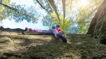 Mädchen klettert mit anderen Pflanzen an einer Wand in einem Wald foto