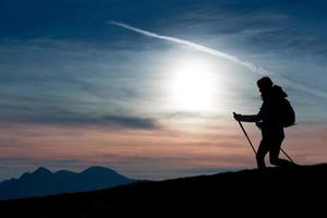 Silhouette eines Mädchens auf einem Berg während einer religiösen Wanderung in einem blauen und orangefarbenen Himmel. foto