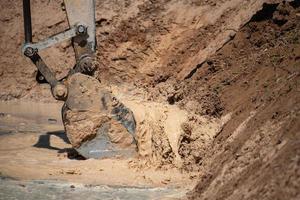 Nahaufnahme der Bulldozer-Maschine, die den Boden gräbt und Sand für Ausgrabungszwecke entfernt foto