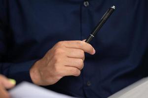 Geschäftsmann, der einen Stift verwendet, um ein Vertragsdokument zu unterzeichnen, das durch Unterschrift genehmigt werden soll, Hand des Geschäftsmanns, der an Vertragsunterlagen für Finanzanwälte im Büro arbeitet, Konzept des Deals auf dem Geschäftsschreibtisch foto