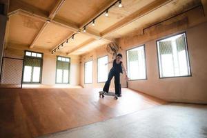 skater-frau, die skateboard in der sporthalle spielt, junge asiatische frau ist glücklich und macht spaß mit dem skateboarding-lebensstil in der stadt, jugendliche hipster-weibliche trendige mode foto