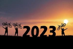 Fahrrad abenteuerlustige Touristen, die Fahrräder über Hindernisse tragen. Frohes neues Jahr 2023 foto