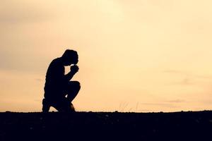 Silhouetten von Männern, die sitzen und um Segen beten. Hoffnungskonzept foto
