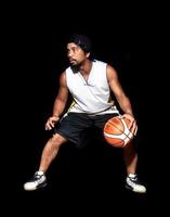 Geste des asiatischen Basketballspielers, der auf schwarzem Hintergrund dribbelt. Basketballkonzept in Asien foto