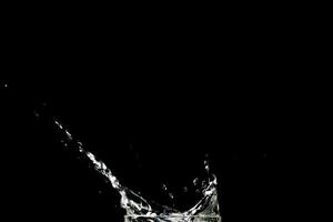 Spritzwasser auf schwarzem Hintergrund. abstrakter hintergrund des wassers, das auf schwarzem hintergrund verbreitet wird foto