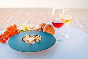 romantisches Abendessen am Strand. Gourmet-Weingläser neben einem schönen Esstisch, Luxus-Resort-Hotel mit Blick auf den Strand foto