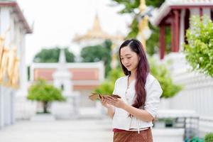 asien frau, die traditionelles kleid von thailand trägt l, das sanskrit altes tripitaka-buch von lord buddha dhamma, heiligtum ratchanatdaram bangkok hält. foto