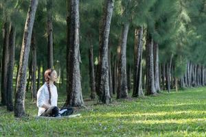 schöne junge Frau, die im Park meditiert und Yoga macht. foto