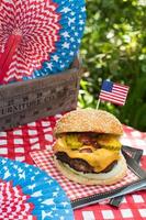 Vierter Juli Käseburger mit amerikanischer Flagge auf dem Picknicktisch im Freien foto