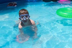 lächelnder kleiner Junge in Schwimmbrillen am Pool foto