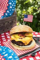 Vierter Juli Käseburger mit amerikanischer Flagge auf dem Picknicktisch im Freien foto