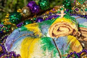 Mardi Gras King Cake mit Krone, umgeben von Perlen und Dekorationen foto