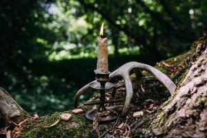 brennende Kerze im Zauberwald. okkultes, esoterisches Konzept. foto