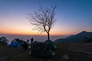 zeltbereich bei sonnenuntergang oder sonnenaufgang auf hügellandschaft campingzelte im wilden berg mit dem touristenreisenden foto