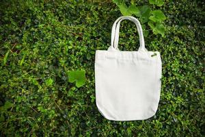 weißer tote canvas stoff öko tasche stoff einkaufssack auf grünem blatt natur hintergrund foto