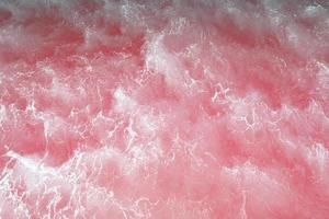 defocus verschwommenes rosafarbenes Wasserspritzen im Meer geplätscherter Wasserdetailhintergrund. wasserspritzer, wassersprayhintergrund. foto