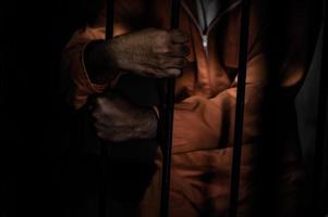 asiatischer mann verzweifelt im eisengefängnis, gefangenenkonzept, thailänder, hoffen, frei zu sein, ernsthafte gefangene, die im gefängnis eingesperrt sind foto