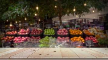 leere hölzerne tischplatte mit unscharfem hintergrund des obstmarktes foto