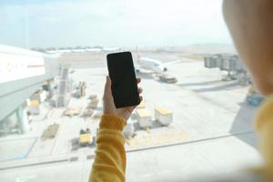 Frau hält Smartphone am Flughafen foto