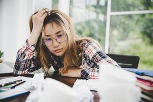 junge frustrierte frau, die im büro arbeitet foto