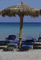 leerer strand - sonnenschirme und sonnenstühle warten auf touristen - elafonisi strand, kreta foto