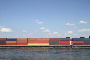 Frachtschiff mit zahlreichen bunten Containern auf einem Fluss