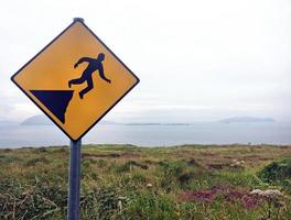 Warnzeichen gefährliche Klippe mit dem Ozean im Hintergrund foto