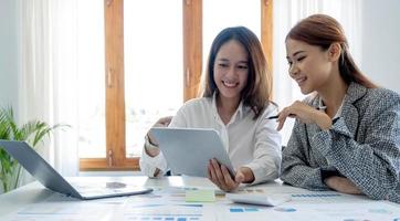 zwei junge Geschäftsfrauen aus Asien, die in Büroräumen zusammenarbeiten foto