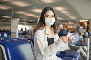 eine reisende frau trägt eine schutzmaske auf dem internationalen flughafen, reise unter einer covid-19-pandemie, sicherheitsreisen, soziales distanzierungsprotokoll, neues normales reisekonzept. foto