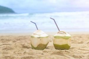 frische kokosnuss mit trinkhalm am strand, reise- und urlaubskonzept. foto