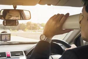 Mann, der Auto mit Navigator fährt und Kaffeetasse hält foto