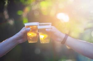 Celebration Beer Cheers Concept - Nahaufnahme von Händen, die während ihres Siegeswettbewerbs oder ihrer erfolgreichen Aufgabenbesprechung Biergläser von Volksgruppen auf Partys im Freien hochhalten foto