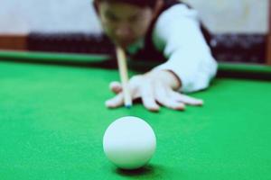 asiatischer Mann, der Snooker spielt und mit seinem Queue auf einen weißen Spielball zielt - Snooker-Spieler im Wettbewerbsspielkonzept foto