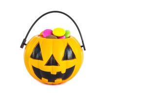 Halloween-Kürbis-Gesicht-Eimer mit bunten Süßigkeiten im Inneren isoliert über weiß foto