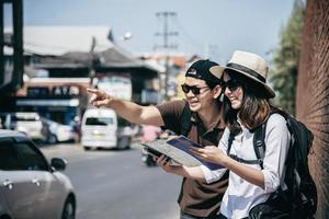 asiatisches rucksackpaar tourist, der stadtplan hält, der die straße überquert - reisen leute urlaub lebensstilkonzept foto