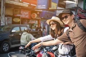 asiatisches rucksackpaar tourist, der stadtplan hält, der die straße überquert - reisen leute urlaub lebensstilkonzept foto