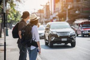 asiatisches rucksackpaar tourist, der stadtplan hält, der die straße überquert - reisen leute urlaub lebensstilkonzept foto