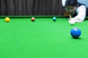 asiatischer Mann, der Snooker spielt und mit seinem Queue auf einen weißen Spielball zielt - Snooker-Spieler im Wettbewerbsspielkonzept foto