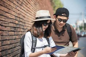 asiatisches rucksackpaar tourist, der stadtplan hält, der die straße überquert - reisen leute urlaub lebensstilkonzept foto