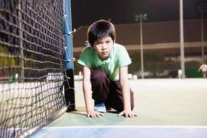 Fröhlicher Junge auf dem Tennisplatz während seiner Trainingszeit - Tennissport mit People-Konzept foto